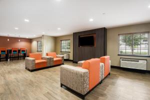 a waiting room with orange chairs and a flat screen tv at Studio 6 Lenexa - Overland Park in Lenexa