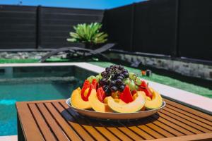 un bol de fruta en una mesa junto a una piscina en Grande Villa cosy avec piscine, sauna & jacuzzi, en Juvignac