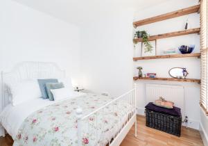 a bedroom with a white bed with a floral bedspread at Near Notting Hill 2 bed Spacious apartment Queens Park Nw6 - QPARK in London