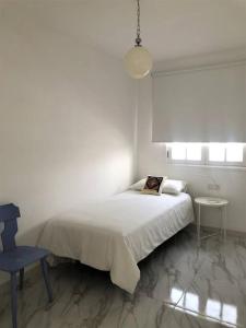 a white bedroom with a bed and a blue chair at Casa Eloína in Playa Honda