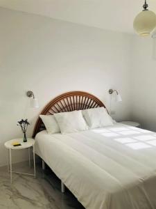 ein Schlafzimmer mit einem großen weißen Bett und einem Tisch in der Unterkunft Casa Eloína in Playa Honda