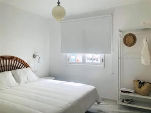 a white bedroom with a bed and a window at Casa Eloína in Playa Honda