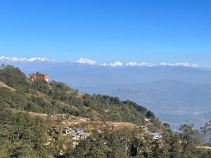 a view of a hill with a lake and mountains at Hotel Nagarkot Holiday Inn in Nagarkot