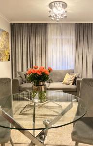ein Wohnzimmer mit einem Glastisch mit Blumen darauf in der Unterkunft Ultra Apartments Kamienica Nova in Stettin