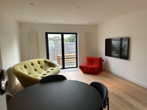 a living room with a table and a red chair at ALTIDO Stylish house with patio in Devon in Ipplepen