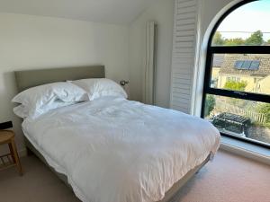 a white bed in a room with a window at ALTIDO Stylish house with patio in Devon in Ipplepen
