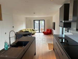 a kitchen with black counter tops and a living room at ALTIDO Stylish house with patio in Devon in Ipplepen