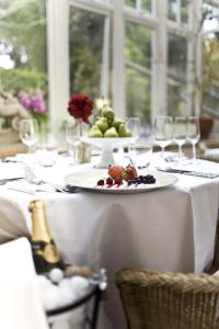 a white table with a plate of fruit and wine glasses at Overcliffe Hotel in Gravesend