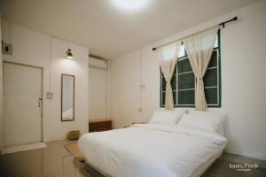 Un dormitorio con una gran cama blanca y una ventana en Baannok cottages Lamphun en Ban Makok