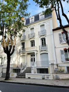um grande edifício branco com escadas em frente em La Villa des Oiseaux - Coeur de Vichy em Vichy