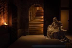 une statue dans une chambre sombre avec un escalier dans l'établissement The Venice Venice Hotel, à Venise