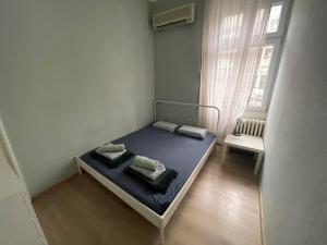 Un pequeño dormitorio con una cama azul y una ventana en Habitat Hostel en Belgrado