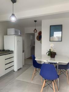 a kitchen with a white table and blue chairs at Pousada BC Flat 300 m da Praia e da Roda Gigante in Balneário Camboriú