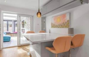 a kitchen with a white counter and orange chairs at MODERN 3 BED - Sleeps 6 with HOT TUB in Bath