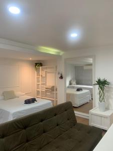 a living room with a couch and a bed and a mirror at Pousada BC Flat 300 m da Praia e da Roda Gigante in Balneário Camboriú