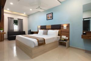 1 dormitorio con 1 cama grande y TV en Grande Inn Trichy, en Tiruchchirāppalli