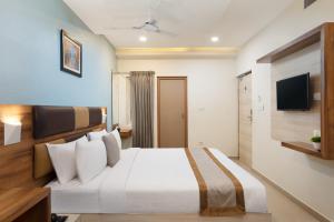 Habitación de hotel con cama y TV en Grande Inn Trichy, en Tiruchchirāppalli