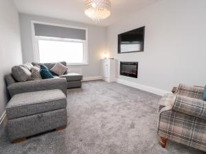 a living room with two chairs and a couch and a television at Ferry View in Fleetwood