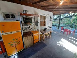 uma cozinha com um frigorífico laranja e uma mesa em Casa Estilosa e Rústica com Vista para o Pôr do Sol da Ilha do Mel! em Convento