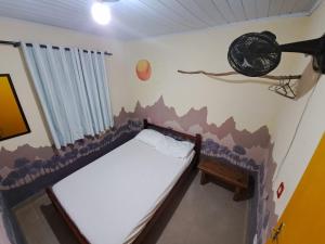 un pequeño dormitorio con una cama y una pared con un arma en Casa Estilosa e Rústica com Vista para o Pôr do Sol da Ilha do Mel!, en Convento