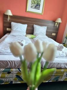 a bedroom with a bed with white sheets and white flowers at Hotel Formanka in Hustopeče