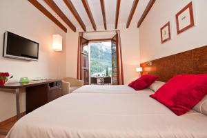1 dormitorio con 1 cama blanca grande con almohadas rojas en Hotel y Apartamentos DES PUIG, en Deià