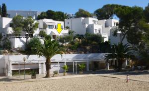 ein weißes Gebäude mit einem gelben Pfeil darauf in der Unterkunft Beach Suite Playa Cala dor in Cala d´Or
