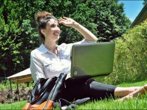 a woman sitting on the grass with a laptop at eduCARE Hotel in Treffen