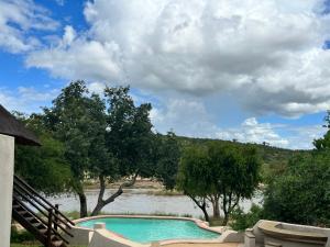 a swimming pool with a river in the background at Nyati Safari Lodge in Balule Game Reserve