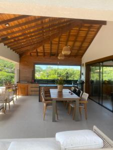 sala de estar con techo de madera, mesa y sillas en Casa alto padrão a 100 metros da praia brava, en Búzios