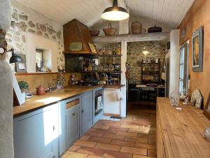 a large kitchen with blue cabinets and a wooden floor at Cottage chaleureux avec piscine privée in Sainte Anastasie - Aubarne
