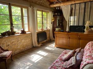 1 dormitorio con 1 cama, TV y ventanas en Cottage chaleureux avec piscine privée, en Sainte Anastasie - Aubarne