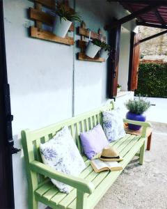 a green bench with pillows and books on a patio at Appartamento Lavanda - Casa vacanza nel Delta del Po 