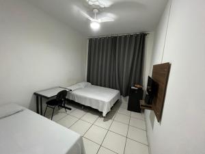um quarto com 2 camas, uma secretária e uma televisão em Hotel Barroco em Belo Horizonte