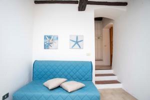 un divano blu in una camera bianca con due cuscini di A Casa di Peter Pan a Capoliveri