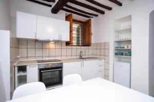una cucina con armadietti bianchi ed elettrodomestici bianchi di A Casa di Peter Pan a Capoliveri