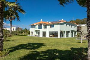 a large white house with a yard with palm trees at Wonderful Villa near Lisbon in São Domingos de Rana