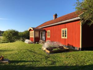 uma casa vermelha com uma estufa em frente em Änden på Säby Tjörn em Säby