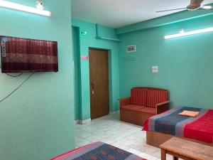 um quarto com uma televisão, uma cama e uma cadeira em Hotel Shahin Residential Jatrabari em Daca