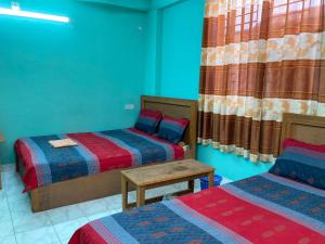 a room with two beds and a table and curtains at Hotel Shahin Residential Jatrabari in Dhaka