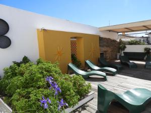 un patio con sillas verdes, plantas y flores en Alandroal Guest House, Hotel, en Alandroal