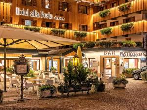 a restaurant with tables and chairs in front of a building at Hotel Alla Posta - Famiglia Pra dal 1866 a Caprile in Alleghe