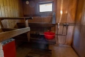 a bathroom with a red bucket and a shower at Aurantola in Jaala