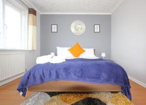 a bedroom with a bed with a blue blanket at Cheerful 3 Bedroom 2 Bathroom Bungalow by CozyNest in Earley