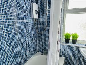 赫斯華爾的住宿－Premium 4 Bed Detached in Heswall，蓝色瓷砖浴室配有淋浴和盥洗盆