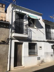 un edificio blanco con ventanas de barrotes negros en Casa Tía Daniela, en Casas de Millán