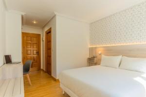 a bedroom with a large white bed and a desk at Hostal Gran Duque in Piedrahita