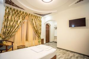 a room with a table and a tv on a wall at AYUB Boutique Hotel in Bukhara