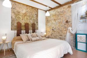 1 dormitorio con cama blanca y pared de piedra en La Casa Arabe, en Alcalá de los Gazules