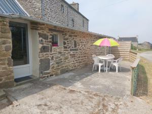 einen Tisch und Stühle mit einem Regenschirm vor einem Gebäude in der Unterkunft Gîte 2 Personnes- Rénové - Plage à 5 min - Parking Gratuit in Lampaul-Ploudalmézeau